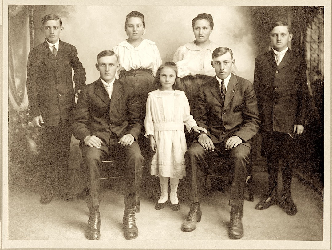 Portrait of the children of John and Kathryn Klaus likely taken in Windsor, Colorado circa 1916. From left to right: Jake (b. 1905), Nick (b. 1900), Annie (b. 1903), Mary (b. 1911), unknown woman, Henry (b. 1898), and John (b. 1908). Courtesy of Elizabeth Lien.